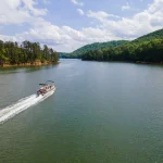 Pontoon boat traveling at full throttle across open lake. Party barge on Lake Altoona during the summer.