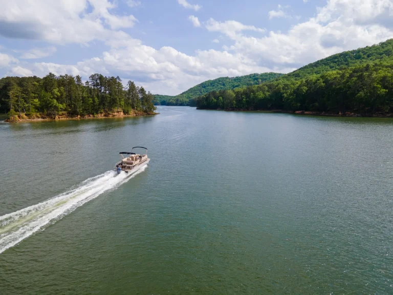 Pontoon boat traveling at full throttle across open lake. Party barge on Lake Altoona during the summer.
