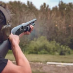 man in soundproof headphones shoots a hard disk at flying plates