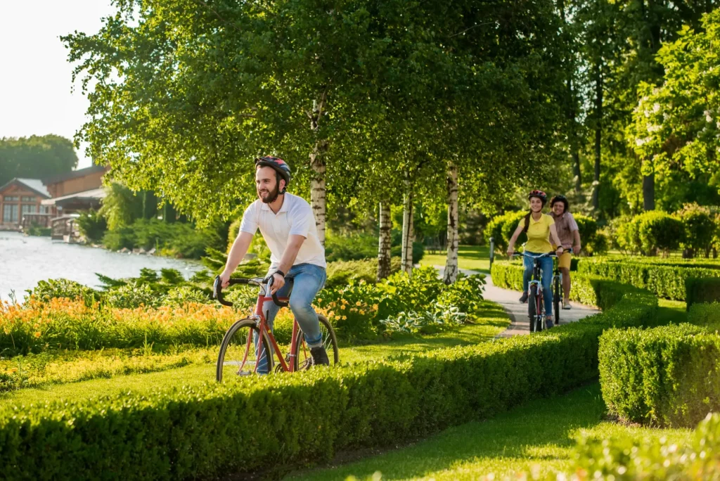 Friends riding bikes in park together. Active students cycling in city park. People, leisure and lifestyle concept.