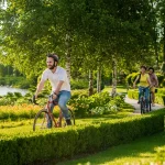 Friends riding bikes in park together. Active students cycling in city park. People, leisure and lifestyle concept.