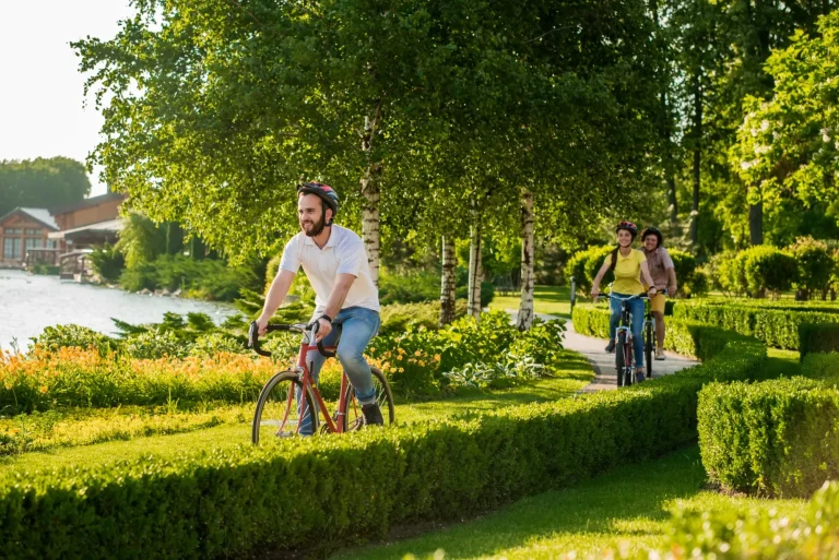 Friends riding bikes in park together. Active students cycling in city park. People, leisure and lifestyle concept.
