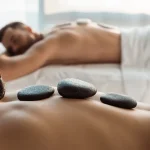 selective focus of woman having stone massage near man in spa center