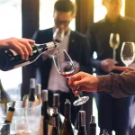 pouring red wine from the bottle into glasses