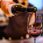 Pouring glass of red wine from a bottle.